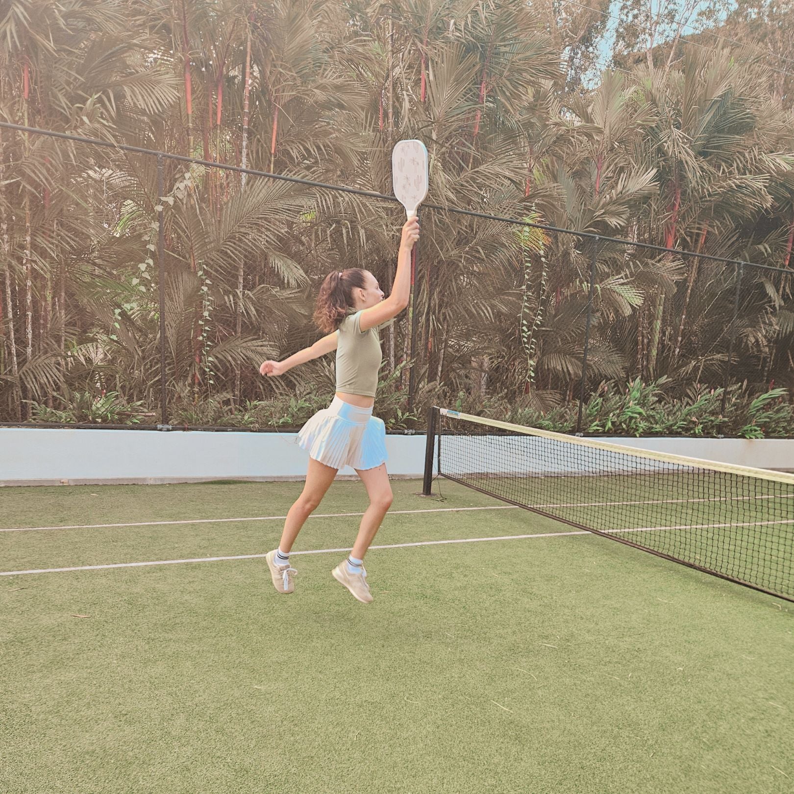 Female pickleball player mid shot with a palm pattern pickleball paddle