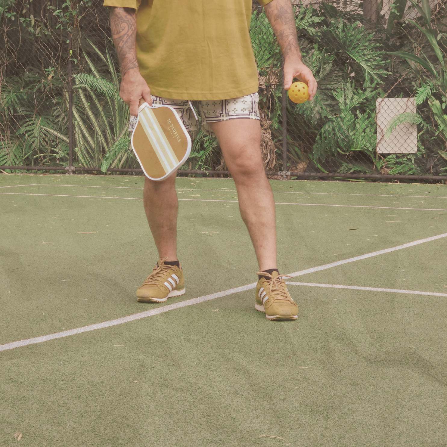 Male playing pickleball with a neutral coloured paddle